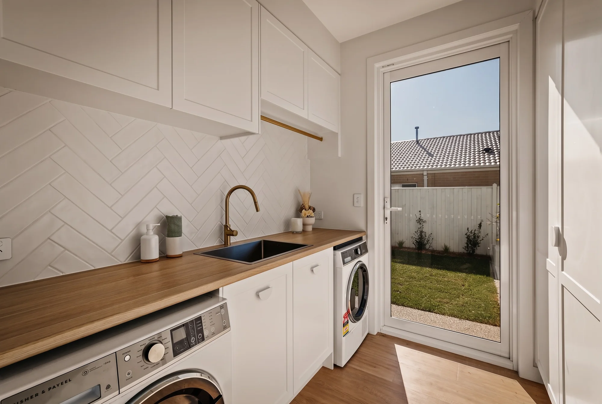 Laundry with herringbone tiles and a timber benchtop
